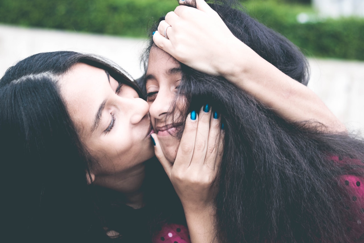 woman-kissing-cheek-of-girl-wearing-red-and-black-polka-dot