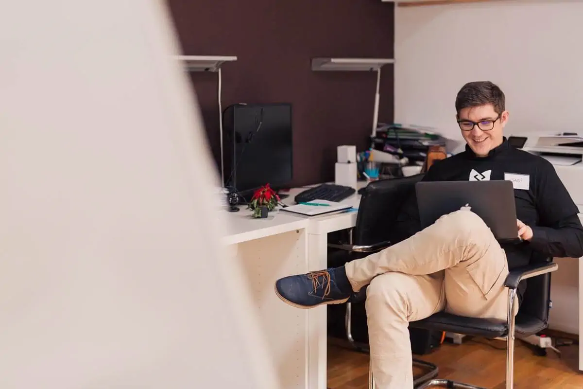 man-smiling-while-sitting-and-using-MacBook