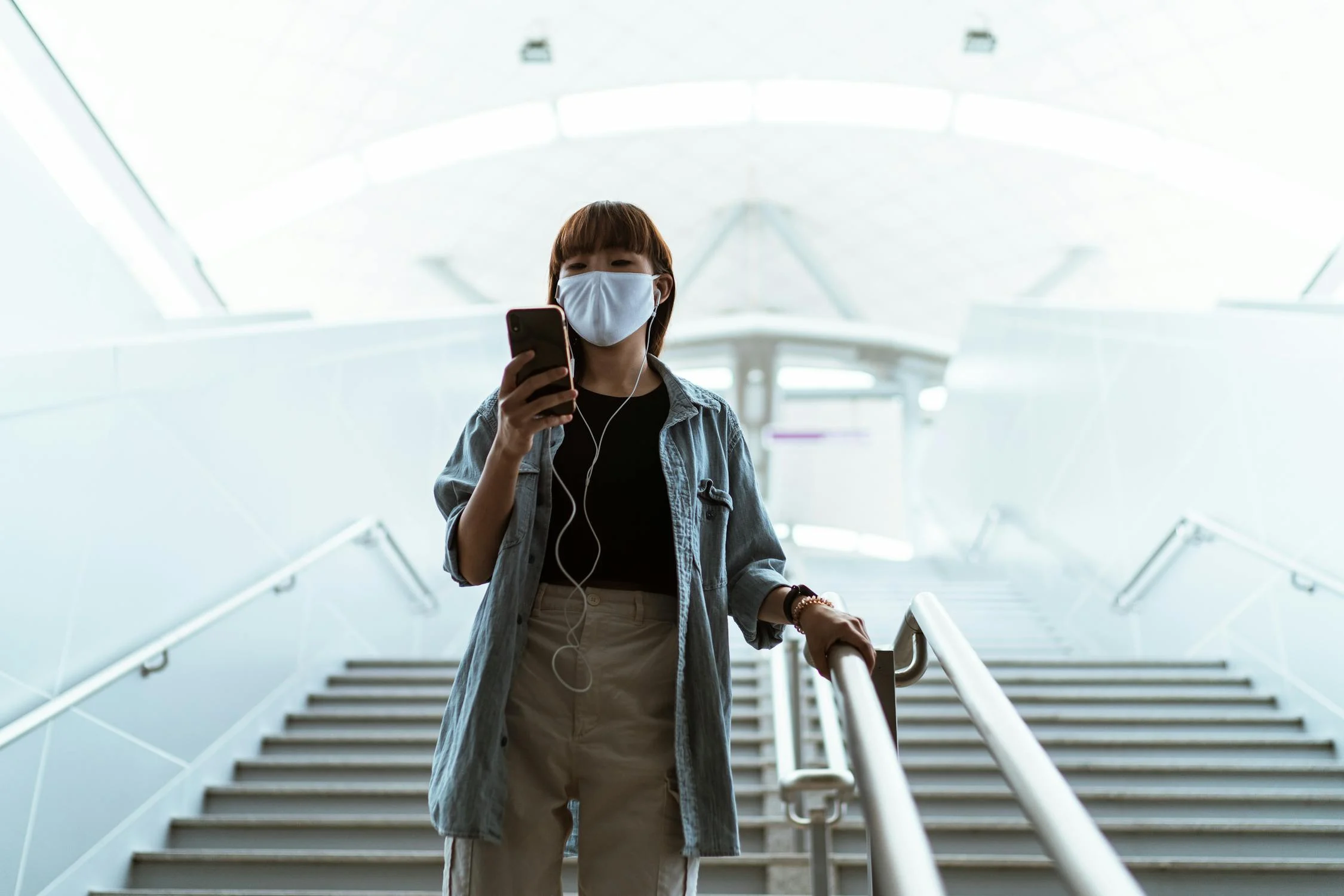 woman wearing a face mask and holding a smartphone