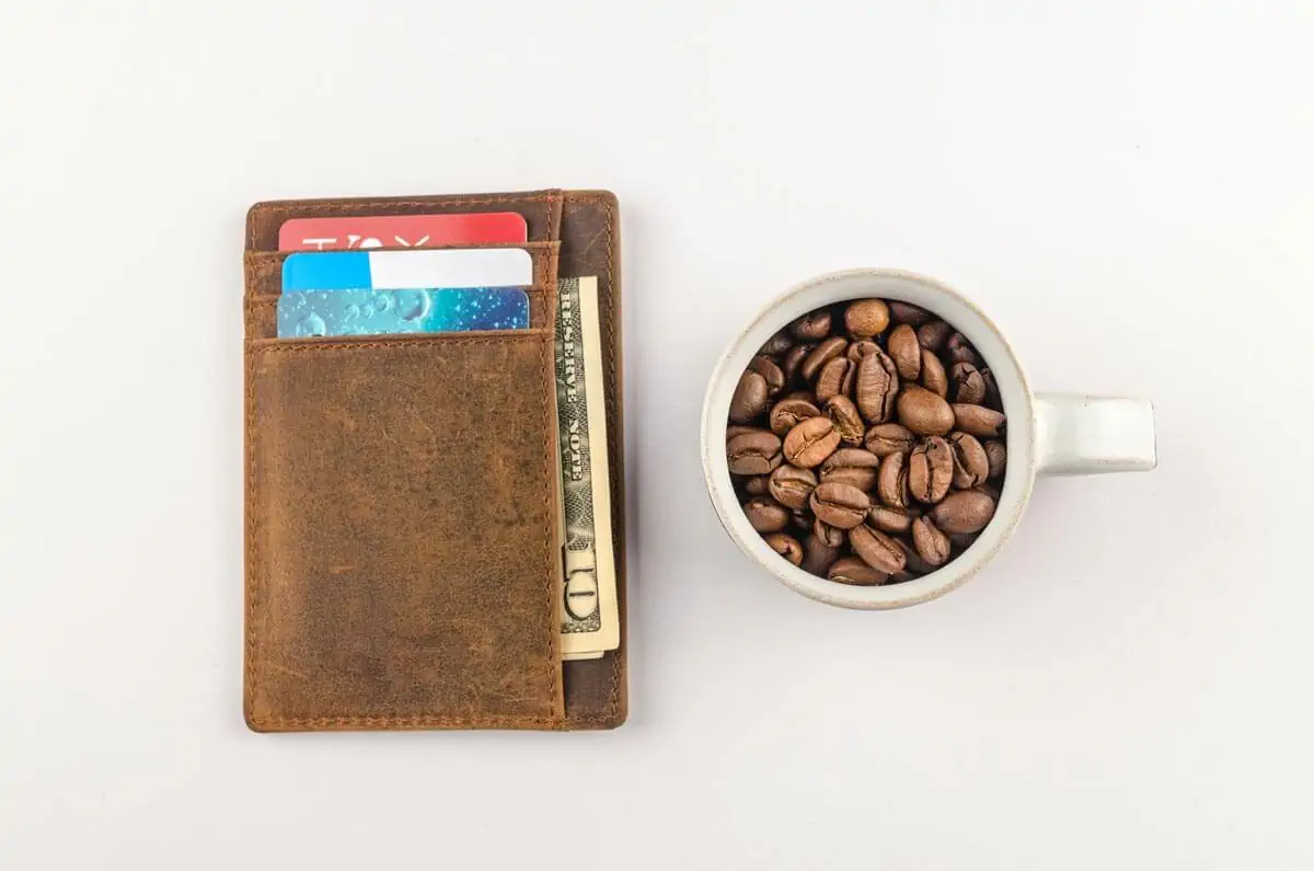 white mug with coffee beans beside brown wallet